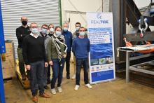 RealTide researchers waering face masks and standing socially distanced beside a RealTide poster
